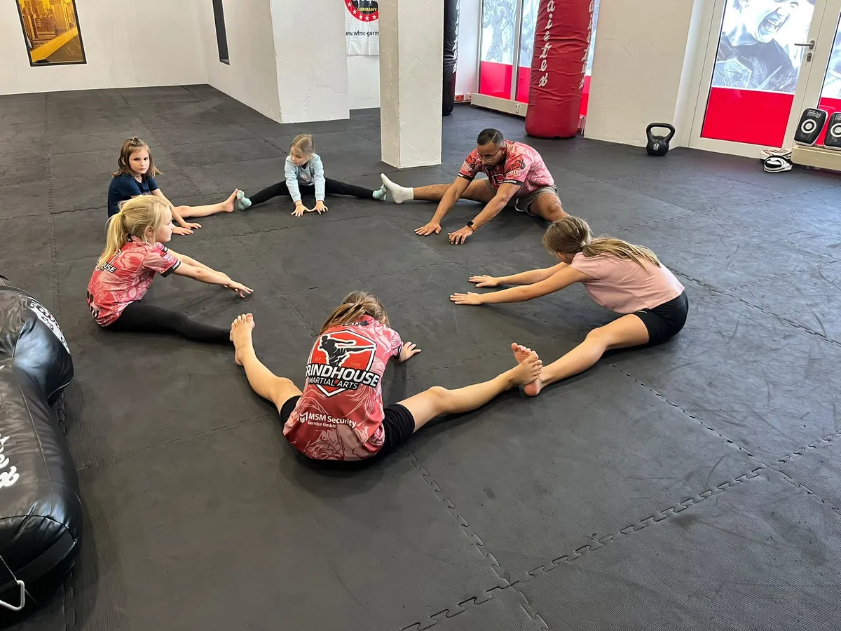 Kinder dehnen im Kreis auf der Matte beim FitKids-Training